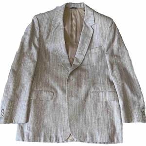 May include: A light beige blazer with vertical striped pattern. The blazer has a notched lapel, two front pockets, and three buttons on each cuff. The interior lining is a solid beige color.