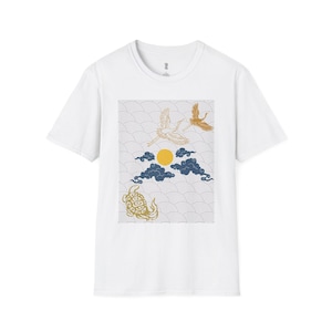 以下が含まれることがあります： 日本のデザインにインスパイアされた白いTシャツ。デザインには、黄色い太陽、青い雲、金色の鶴とカメが含まれています。背景には波模様があります。