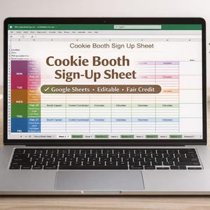 Puede incluir: Un ordenador portátil muestra una "Cookie Booth Sign-Up Sheet" en formato de hoja de cálculo. La pantalla muestra una tabla colorida con columnas para fechas, horas y roles de voluntarios. El portátil está sobre un escritorio de madera, junto a una taza, un bloc de notas, un bolígrafo y una pequeña planta en maceta.