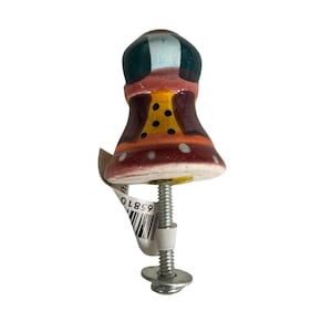 May include: A ceramic cabinet knob with a bell-shaped design featuring a dark teal top, a yellow midsection with black polka dots, and a wide maroon base with white dots. A metal bolt with a washer and a white barcode tag is attached to the bottom.
