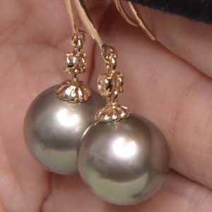 May include: A pair of gold dangle earrings with a gray pearl and a small diamond accent.