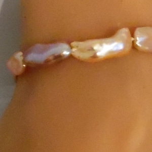 May include: A bracelet made of a string of irregular shaped, iridescent pink and white pearls.