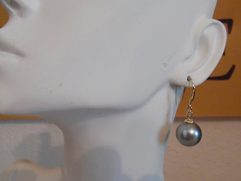May include: A pair of gold dangle earrings with a single dark gray pearl on each earring.