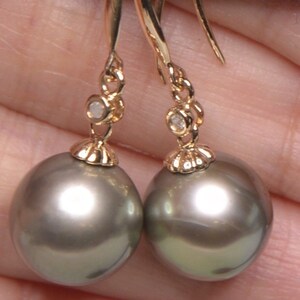 May include: A pair of silver pearl drop earrings with a small diamond accent on each earring. The earrings are suspended from a gold chain.
