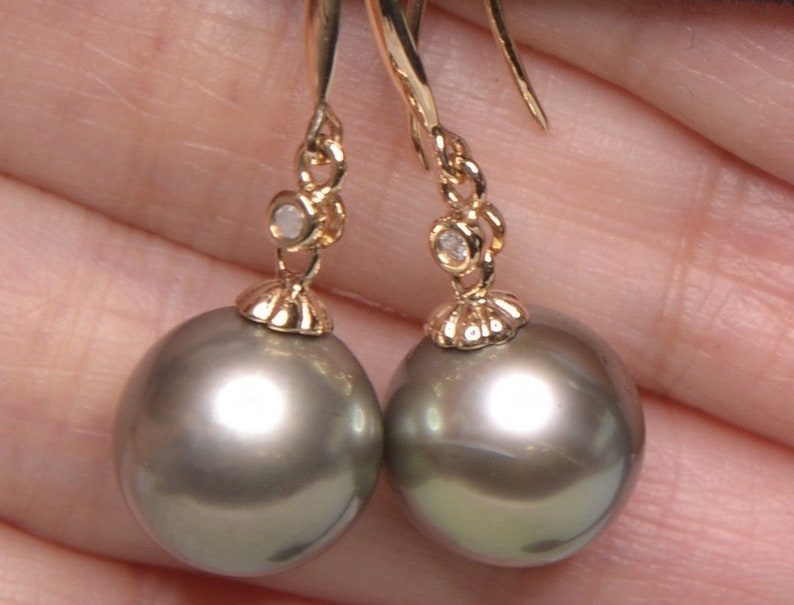 May include: A pair of silver pearl drop earrings with a small diamond accent on each earring. The earrings are suspended from a gold chain.