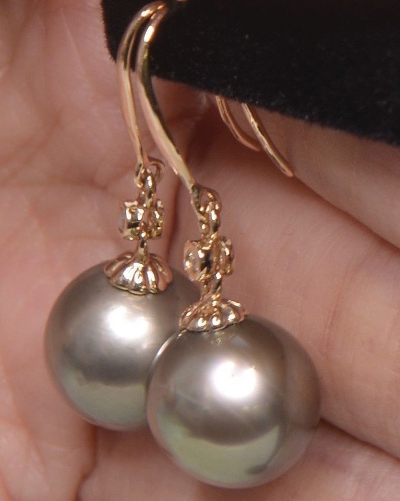May include: A pair of gold dangle earrings with a gray pearl and a small diamond accent.