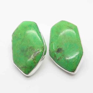 May include: A pair of silver earrings with green gemstone cabochons. The stones are irregularly shaped and have a mottled green color.