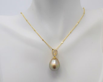 May include: A gold chain necklace with a teardrop-shaped pearl pendant. The pendant is surrounded by a halo of small clear stones.