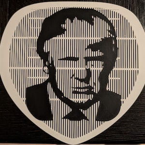 Puede incluir: Retrato de ilusión óptica en blanco y negro. La imagen presenta el rostro de una persona creado por líneas verticales negras sobre un fondo blanco. La forma es un rectángulo redondeado.