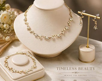 Set di gioielli floreali: collana, bracciale e orecchini color oro con dettagli in cristallo.