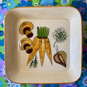 May include: A square, off-white ceramic serving tray with rounded corners and a brown border. The tray features hand-painted illustrations of mushrooms, carrots, a tree, and a root vegetable. The vegetables are yellow and orange with green accents.