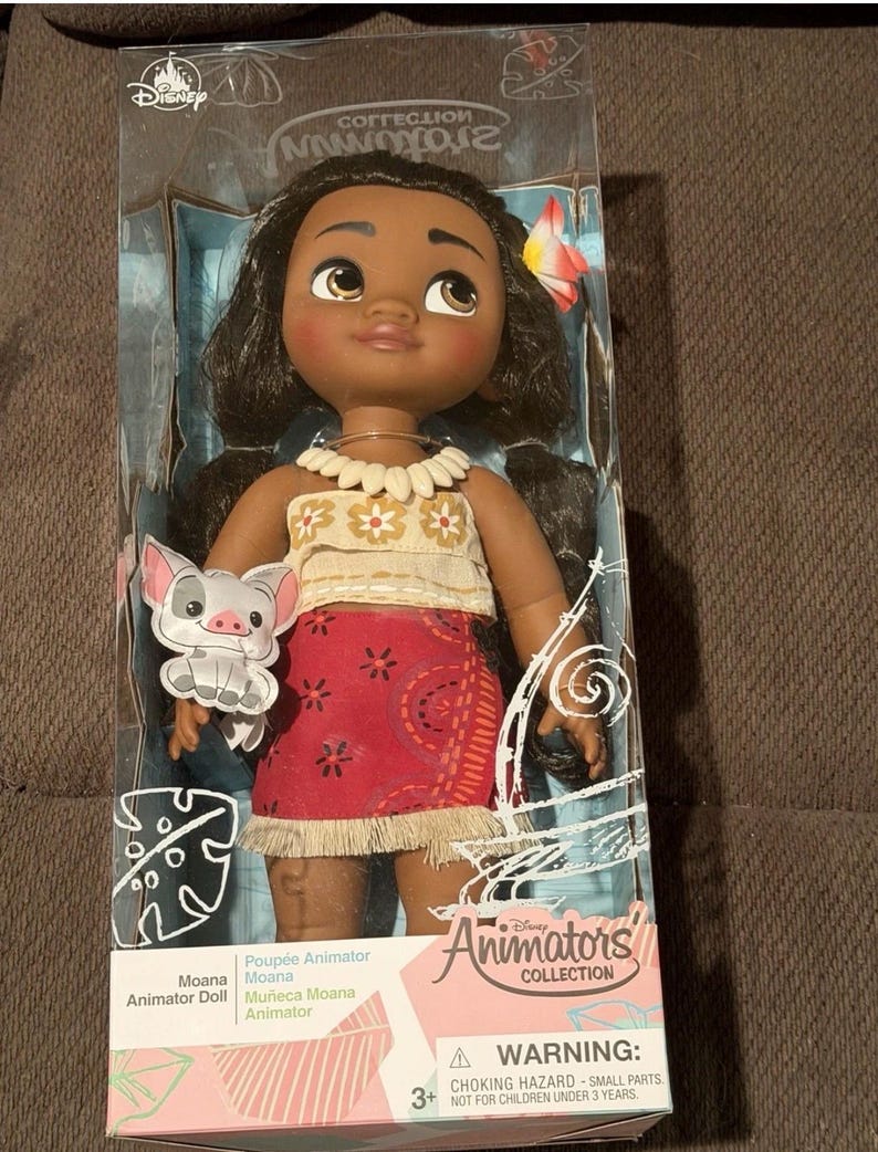 Puede incluir: Mu&ntilde;eca Moana de la colecci&oacute;n Disney Animators en una caja de pl&aacute;stico transparente. La mu&ntilde;eca tiene cabello oscuro, ojos marrones y un accesorio floral para el cabello. Viste un top beige, una falda roja con estampados florales blancos y un collar de conchas. Incluye un cerdito.