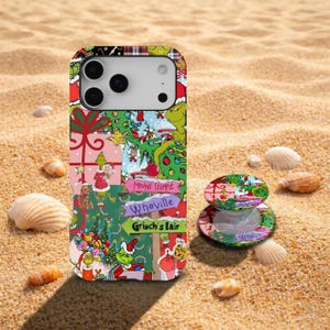 Könnte beinhalten: Eine Smartphone-Hülle und ein passender runder Handyhalter mit einer farbenfrohen Collage zum Thema Feiertage. Das Design zeigt Illustrationen einer grünen Figur, Weihnachtsbäume, Geschenke und Schilder mit der Aufschrift Mount Crumpit, Whoville und Grinch's Lair.