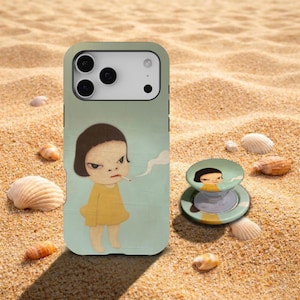 May include: A phone case and phone grip featuring a cartoon illustration of a girl in a yellow dress smoking a cigarette. The phone case is light green with the illustration on the back. The phone grip is light green and yellow.