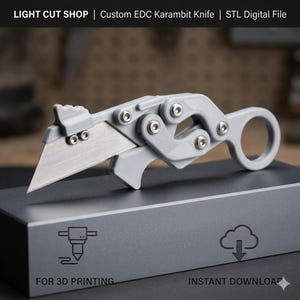 May include: A grey karambit-style utility knife with a metallic blade and a ring handle, featuring mechanical joints secured by silver screws. The text LIGHT CUT SHOP | Custom EDC Karambit Knife | STL Digital File is visible above.