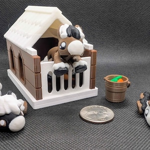 以下が含まれることがあります： 茶色と白の屋根が付いたミニチュアの馬小屋、中に茶色と白の馬の置物、そして横たわっている2つの馬の置物。緑とオレンジの物体が入った小さな茶色のバケツが近くにあります。画像にはコインも含まれています。