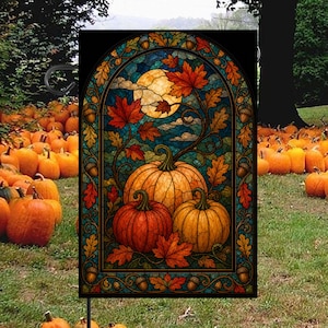 May include: A rectangular garden flag featuring a stained glass style illustration of three orange pumpkins surrounded by autumn maple leaves and acorns. The design is set within an arched frame against a dark blue sky with a full moon.