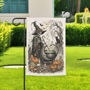 May include: A rectangular garden flag featuring a detailed black and white illustration of a skeleton wearing a witch hat and robe, stirring a crescent moon-shaped cauldron. The scene includes pumpkins, a black cat, a skull, and a willow tree.