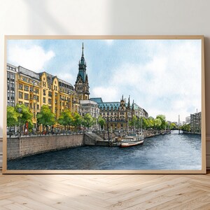 Peut inclure: Une illustration à l'aquarelle d'un canal urbain avec des bâtiments jaunes, une haute tour d'horloge, des arbres verts et un bateau blanc amarré le long d'un quai en pierre sous un ciel bleu clair. L'œuvre est dans un cadre en bois clair.