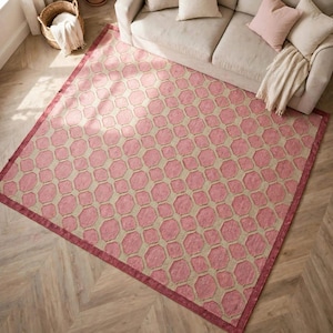 May include: A rectangular area rug featuring a repeating geometric pattern of pink octagons set against a light beige background, finished with a solid pink border that frames the entire design across the surface of the floor covering.