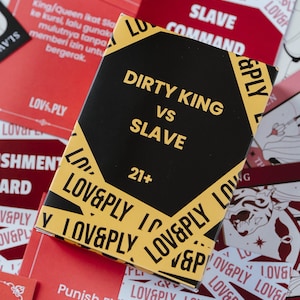 May include: A black and yellow box with the text "DIRTY KING vs SLAVE" and "21+". The box is surrounded by red and white cards with the words "LOVE&PLY" and "SLAVE COMMAND".