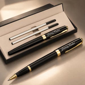 May include: Two black ballpoint pens with gold-tone accents and clips, each engraved with the name Jimmy Hunter in white script. The set includes two silver-tone ink refills, all presented in a black rectangular gift box with a beige interior.