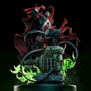 May include: A detailed figurine of the comic book character Spawn, posed atop a stone structure. The figure is clad in a black and red costume with a flowing red cape. Green, glowing energy emanates from the base, and a chain wraps around the figure.