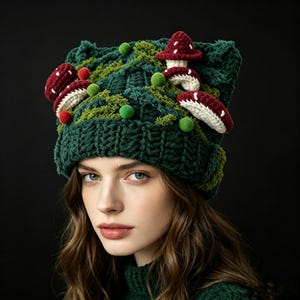 May include: A dark green crocheted beanie featuring a textured cable knit pattern. The hat is decorated with several three-dimensional crocheted mushrooms in deep red and white, along with small green pom-poms and green yarn accents.