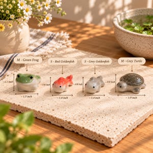 May include: Four ceramic animal figurines: a green frog measuring 1.5 by 1.1 inches, a red goldfish measuring 1.4 by 0.8 inches, a grey goldfish measuring 1.4 by 0.8 inches, and a grey turtle measuring 1.9 by 0.9 inches, labeled with text.