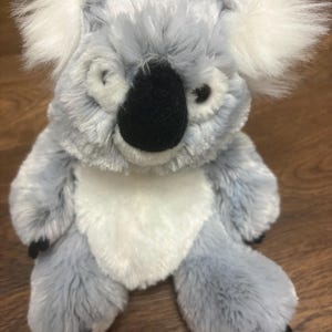 May include: A plush koala bear toy with gray fur, white accents, and a black nose. The koala has large, fluffy white ears and black paws. The toy is designed to resemble a real koala.