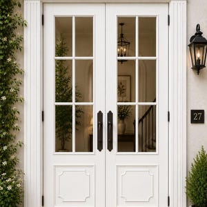 Pode incluir: Uma porta dupla branca com seis painéis de vidro de cada lado, com puxadores de metal escuro e uma moldura decorativa no topo. A estrutura da porta inclui pilares laterais canelados e uma placa preta com o número 27 na parede ao lado.
