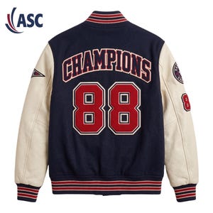 May include: A navy blue varsity jacket with cream-coloured sleeves. The back features the word CHAMPIONS in red letters above the large red number 88. The collar and cuffs have red and white stripes. A circular patch and the number 8 are on the sleeve.