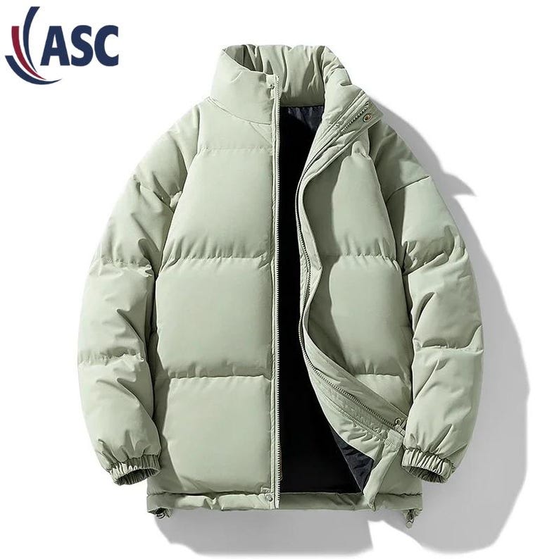 May include: A light green puffer jacket with a high collar and a full-length zipper. The jacket has a quilted design and elastic cuffs. The logo "ASC" is in the upper left corner. This winter coat is designed for warmth and comfort.