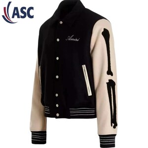 May include: Black and cream-colored varsity jacket with bone-shaped designs on the sleeves. The jacket features a button-up front, a zippered pocket, and the embroidered word "Amiri" on the chest. The cuffs and hem have black and cream-colored stripes.
