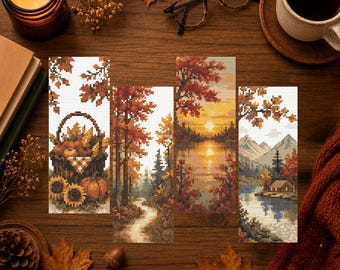 May include: Four rectangular cross-stitch bookmarks featuring autumn scenes: a basket with pumpkins and sunflowers, a forest path with orange trees, a sunset reflecting over a lake, and a cabin by a mountain lake with colorful fall foliage.