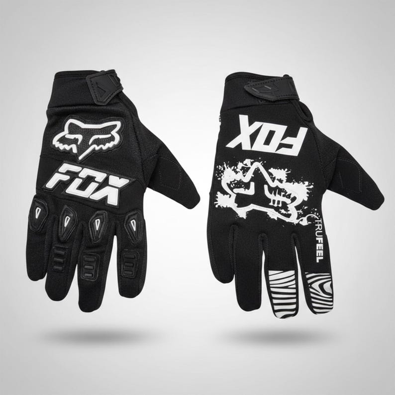 Puede incluir: Un par de guantes de carreras Fox negros con logotipos y detalles en blanco. Los guantes presentan el logotipo y el texto de Fox, con acolchado reforzado en la palma y los dedos. Tienen correas de mu&ntilde;eca ajustables.