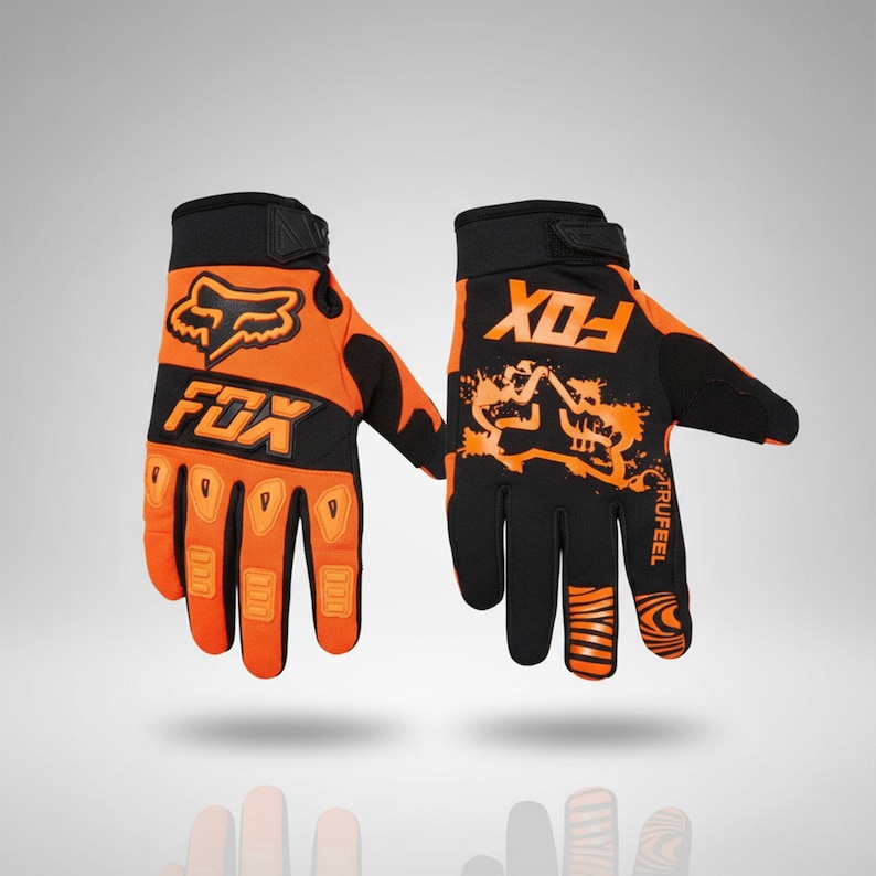Puede incluir: Un par de guantes de carreras Fox naranjas y negros. Los guantes presentan el logotipo y el texto Fox en negro. Los guantes tienen un cierre de velcro en la mu&ntilde;eca y est&aacute;n dise&ntilde;ados para motocross o todoterreno.