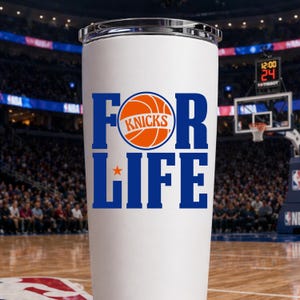 Pu&ograve; includere: Bicchiere bianco con bordo argentato. Il testo "FOR LIFE" &egrave; in blu, con "KNICKS" e una grafica di basket in arancione. Una stella arancione &egrave; sotto "FOR". Lo sfondo mostra un campo da basket e tribune.