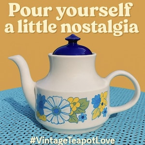 May include: White vintage teapot with a blue lid and floral design in blue, yellow, and green. The teapot has a curved spout and handle. Text on the image reads "Pour yourself a little nostalgia" and "#VintageTeapotLove".