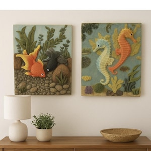 May include: Two framed wall art pieces depicting underwater scenes. One features a goldfish and a black fish, the other showcases two seahorses. The artwork is in shades of orange, yellow, blue, and green, with a textured appearance.