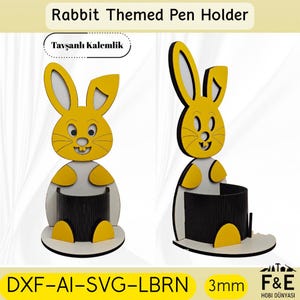 May include: A yellow and white rabbit-themed pen holder. The pen holder has a black pen storage area and is made of wood. The text "Rabbit Themed Pen Holder" is at the top. The text "DXF-AI-SVG-LBRN" is at the bottom.