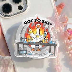 May include: White phone case with a pop-up grip featuring a cartoon goose in a lab coat with the text "GOT TO SILLY". The case has a pink beaded strap and a pink bow. The phone case is held by a person.