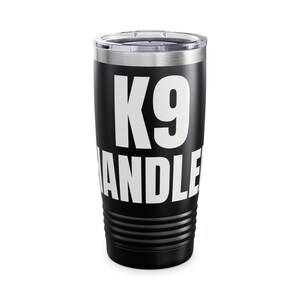 Könnte beinhalten: Schwarzer isolierter Becher mit silbernem Rand und Deckel. Der Becher trägt den Text "K9 HANDLER" in großen weißen Buchstaben. Der Becher ist für heiße oder kalte Getränke geeignet.