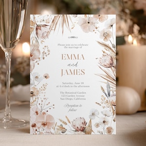 Puede incluir: Una invitación de boda con los nombres "EMMA y JAMES" en tipografía elegante. La invitación está adornada con ilustraciones florales en acuarela en tonos suaves y neutros. El texto incluye la fecha, hora y lugar de la ceremonia.