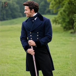 May include: A navy blue tailcoat featuring a double-breasted front with six silver buttons, a high collar, and dark velvet lapel accents. The coat is worn over a white shirt with a dark necktie, paired with black trousers and a light-colored cane.