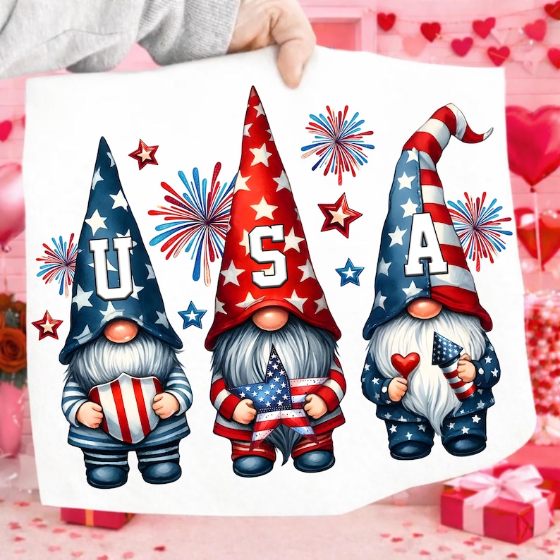 May include: A white print featuring three patriotic gnomes with the letters "USA" on their hats. The gnomes are adorned with red, white, and blue stars and stripes, holding patriotic symbols. Fireworks and stars complete the festive design.