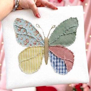 Może przedstawiać: Kolorowa dekoracja w kształcie motyla ze skrzydłami z patchworku. Skrzydła mają wzory kwiatowe, w paski i w kratkę w odcieniach niebieskiego, ż&oacute;łtego, r&oacute;żowego i zielonego. Motyl jest umieszczony na białym tle.