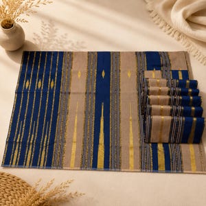 May include: A rectangular fabric placemat featuring a vertical striped pattern in deep blue, beige, and metallic gold. The design includes alternating wide bands of solid blue and beige, accented by thin, shimmering gold lines and small diamond motifs.