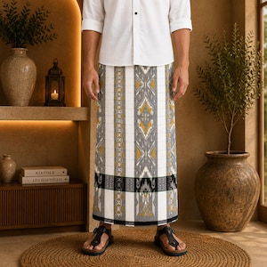 May include: A white button-down shirt paired with a long sarong featuring a vertical pattern in shades of white, gray, black, and mustard yellow. The sarong has a distinct horizontal band near the hem with intricate geometric and floral motifs.