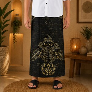 Könnte beinhalten: Ein schwarzer Sarong mit einem komplexen, goldfarbenen Blumen- und Geometriemuster. Der Stoff zeigt im oberen Bereich eine feine, sich wiederholende Kreuzschraffur und im unteren Bereich ein großes, symmetrisches, verziertes Motiv.